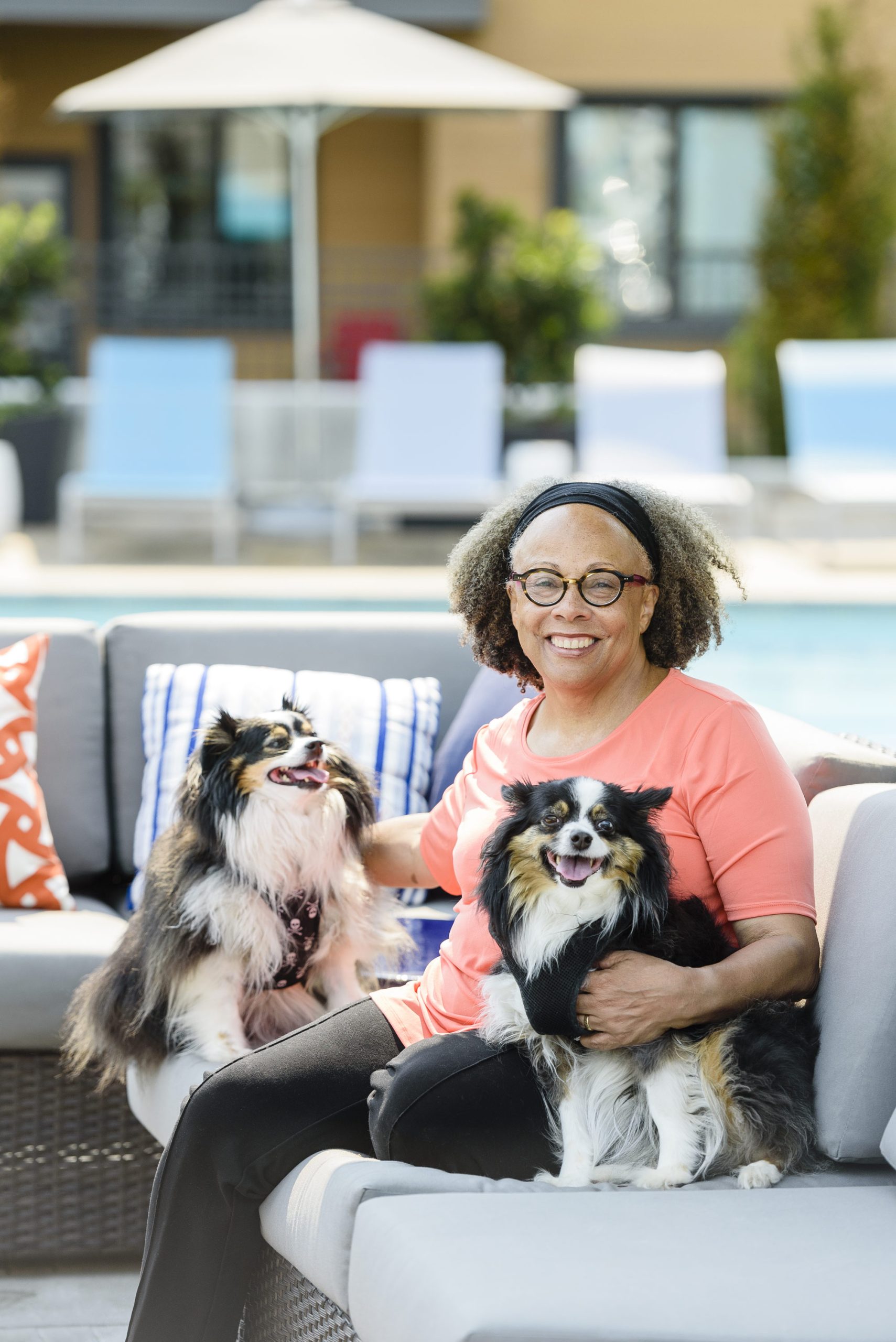 a portrait of Jewell Parker Rhodes near a pool with her two happy dogs